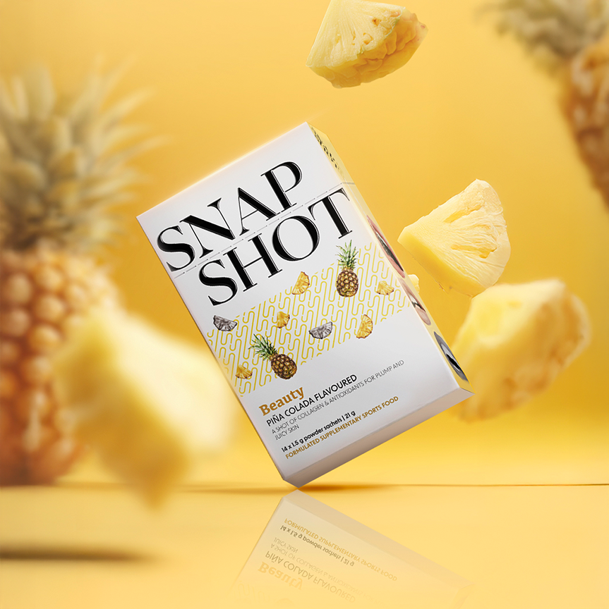 Product packaging labeled 'Snap Shot' with pineapple slices and a whole pineapple on a yellow background