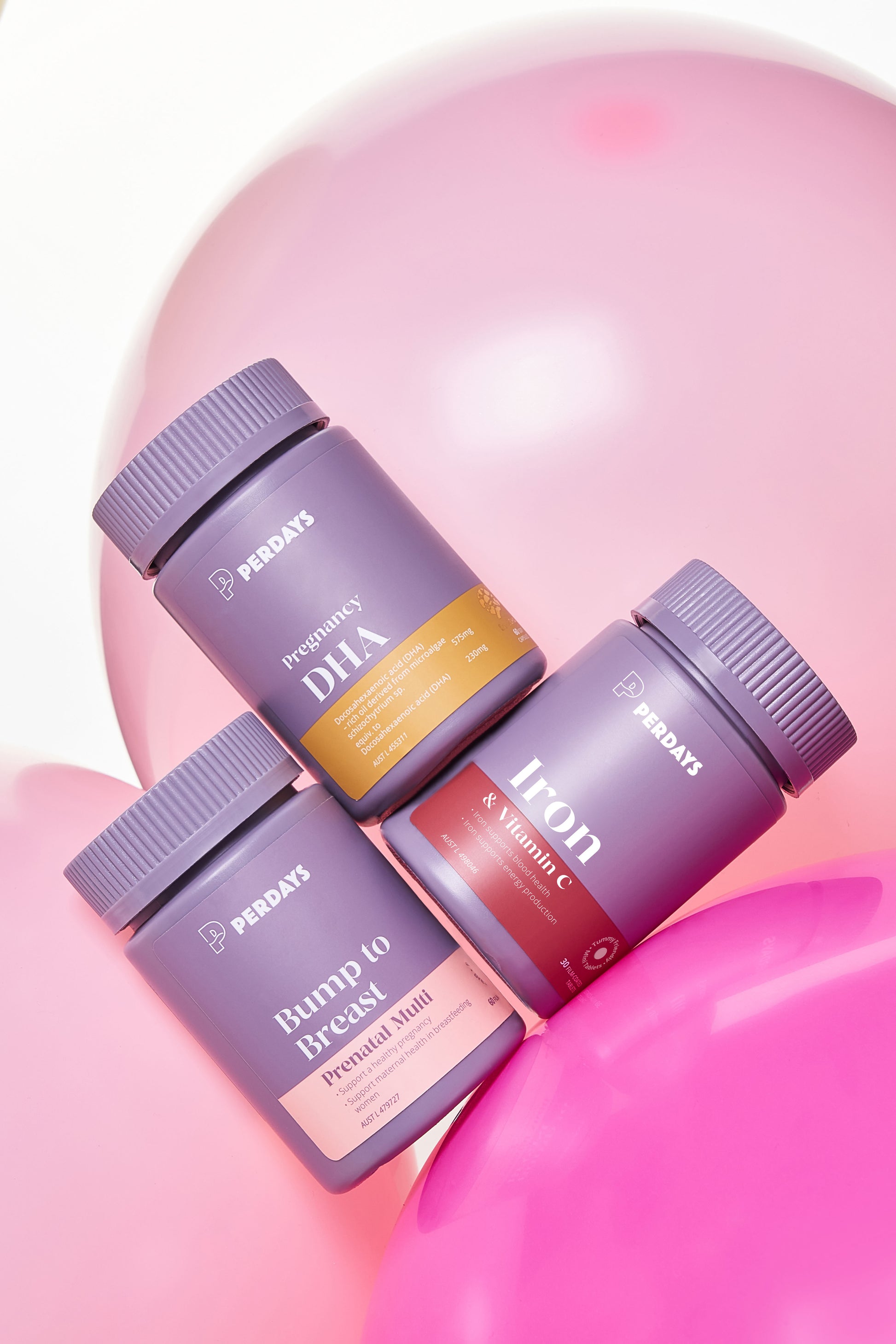 Three purple supplement bottles with different labels on a pink background